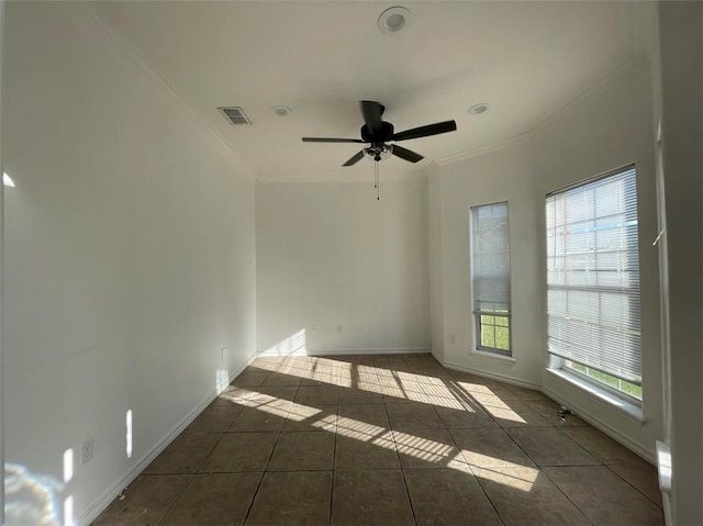 empty room with dark tile patterned flooring, a wealth of natural light, ceiling fan, and crown molding