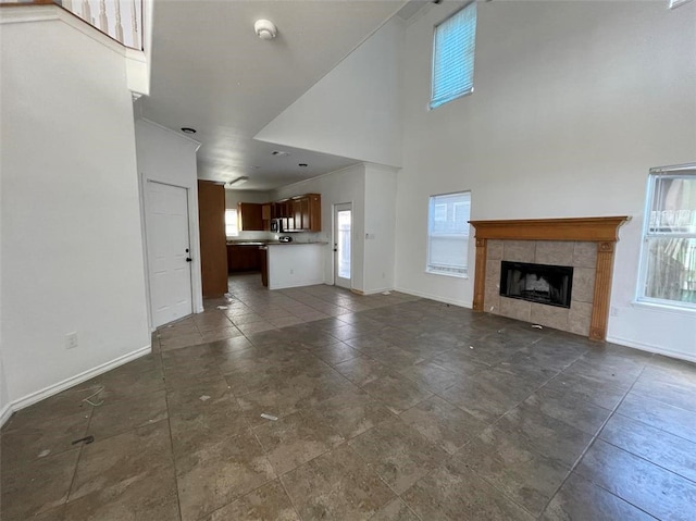 unfurnished living room with a high ceiling, a healthy amount of sunlight, and a fireplace