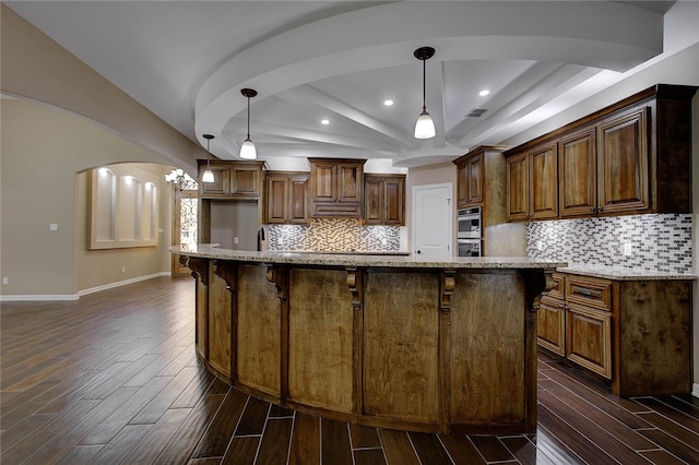 kitchen with hanging light fixtures, dark hardwood / wood-style floors, and a kitchen island with sink