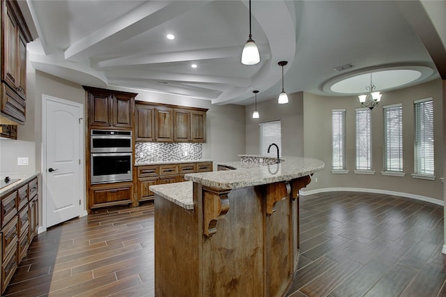 kitchen with pendant lighting, a kitchen breakfast bar, dark hardwood / wood-style floors, a notable chandelier, and stainless steel double oven