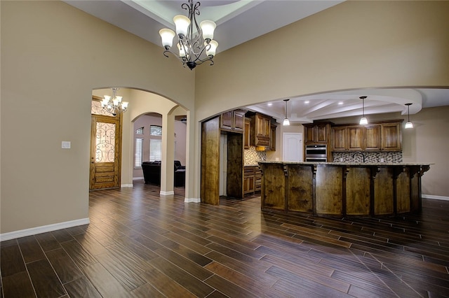 kitchen featuring decorative backsplash, decorative light fixtures, dark wood-type flooring, and a notable chandelier