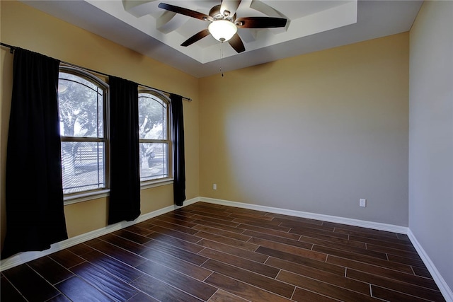 unfurnished room with a raised ceiling, ceiling fan, and dark hardwood / wood-style flooring