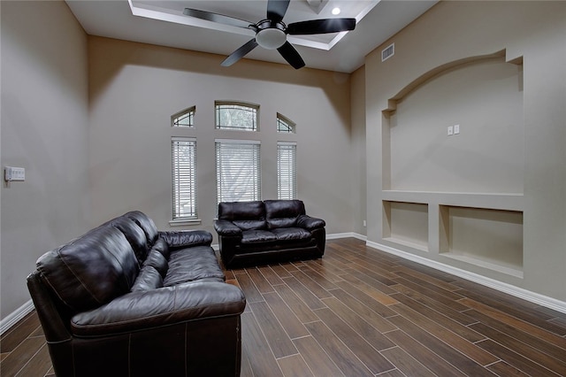 living room with built in shelves, ceiling fan, and dark hardwood / wood-style flooring