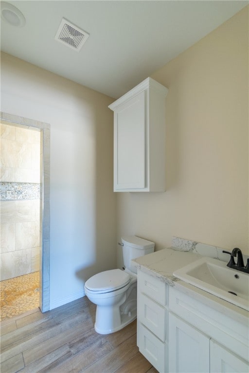 bathroom featuring a shower, wood-type flooring, vanity, and toilet