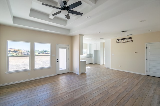 unfurnished living room featuring a tray ceiling, light hardwood / wood-style flooring, and ceiling fan