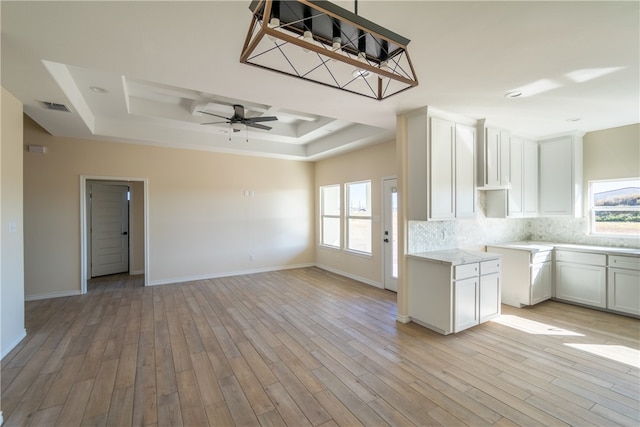 kitchen featuring white cabinets, light hardwood / wood-style floors, and a tray ceiling