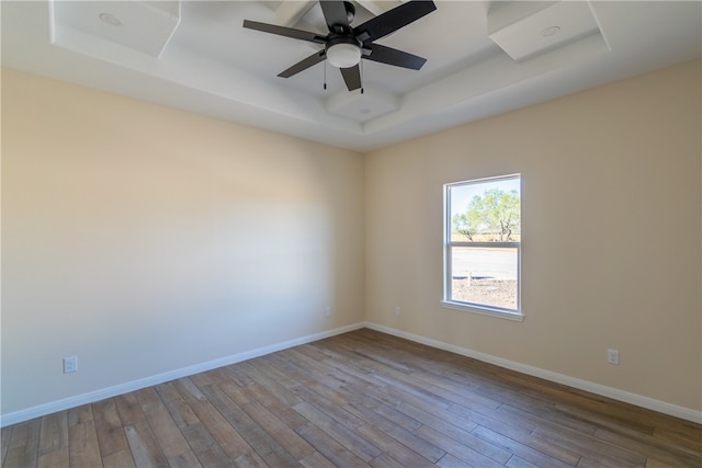 unfurnished room featuring a raised ceiling, ceiling fan, and light hardwood / wood-style flooring