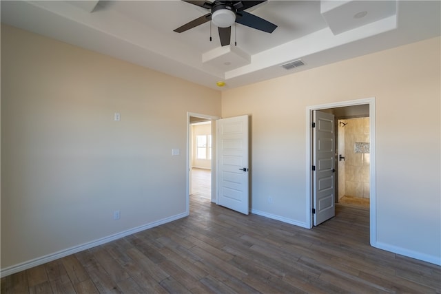 unfurnished bedroom featuring dark hardwood / wood-style floors, ceiling fan, and a tray ceiling