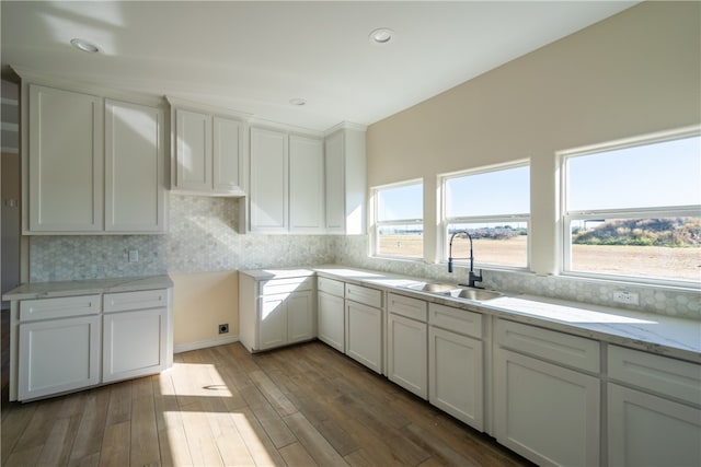 kitchen featuring backsplash, hardwood / wood-style floors, and white cabinets