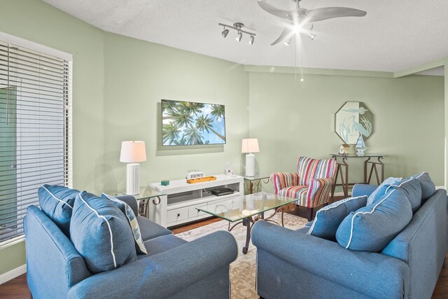 living room with a textured ceiling, hardwood / wood-style flooring, and ceiling fan