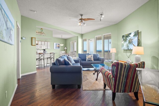 living room with dark hardwood / wood-style flooring, a textured ceiling, and ceiling fan