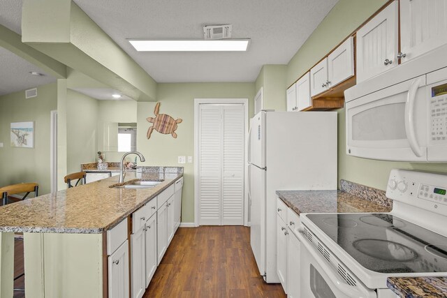 kitchen with white appliances, sink, a kitchen bar, and white cabinets