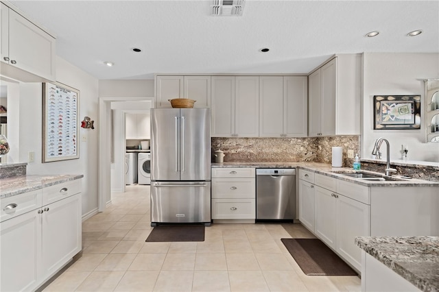 kitchen with stainless steel appliances, sink, tasteful backsplash, light stone countertops, and white cabinets