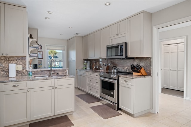 kitchen featuring white cabinets, stainless steel appliances, sink, and light stone countertops