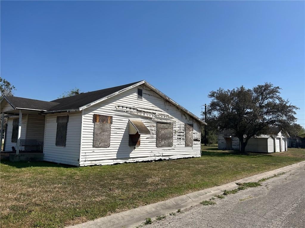 bungalow with a front yard and an outbuilding
