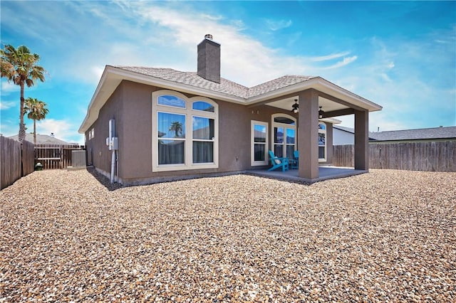 rear view of property with stucco siding, a patio, a chimney, a fenced backyard, and ceiling fan