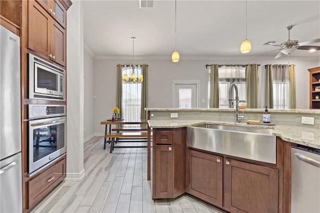 kitchen featuring stainless steel appliances, a sink, crown molding, decorative light fixtures, and a chandelier