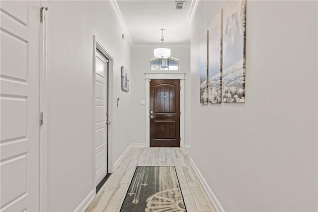 doorway to outside with ornamental molding, baseboards, and light wood finished floors