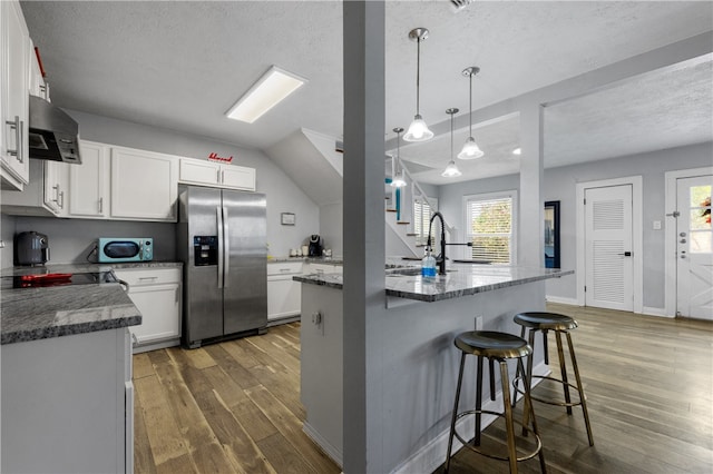 kitchen featuring dark wood-type flooring, white cabinetry, stainless steel fridge with ice dispenser, and exhaust hood