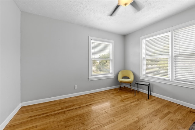 unfurnished room featuring ceiling fan, a healthy amount of sunlight, light hardwood / wood-style floors, and a textured ceiling