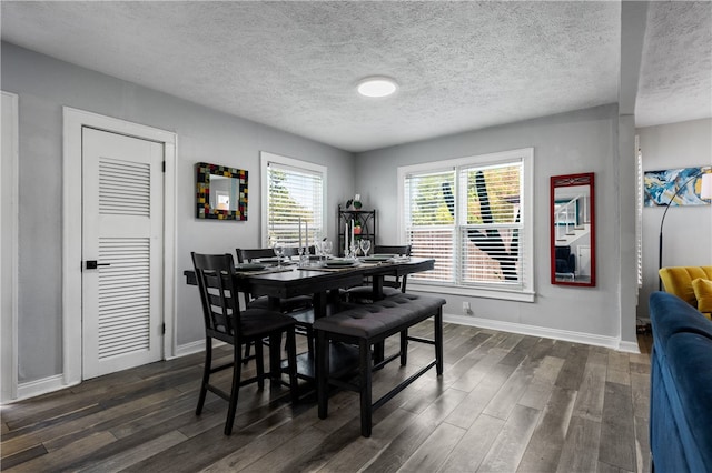 dining space featuring dark wood-type flooring and a textured ceiling