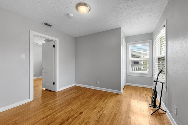 empty room featuring a textured ceiling and light hardwood / wood-style flooring