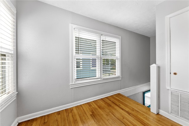 unfurnished room with hardwood / wood-style floors and a textured ceiling