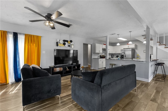 living room featuring hardwood / wood-style floors, a textured ceiling, and ceiling fan