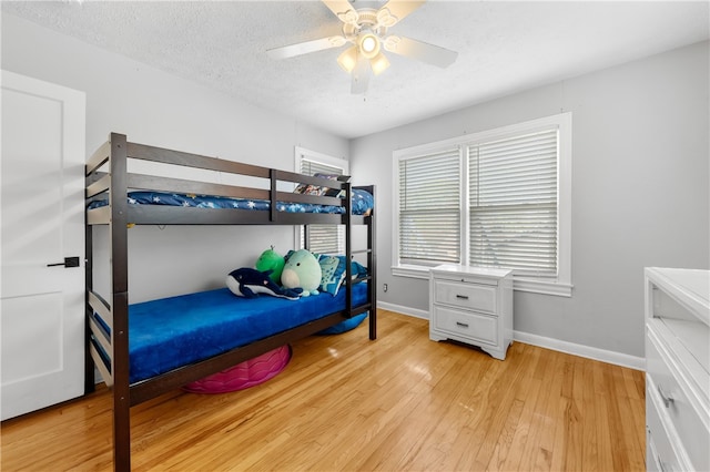 bedroom featuring light wood-type flooring, a textured ceiling, and ceiling fan