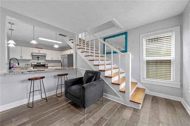 staircase with sink, wood-type flooring, and a textured ceiling