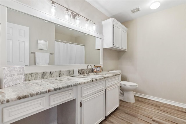 full bath featuring vanity, wood finished floors, visible vents, baseboards, and toilet