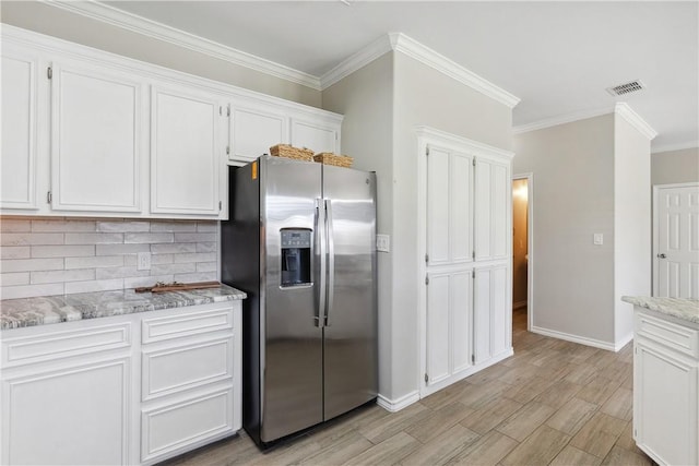 kitchen with ornamental molding, stainless steel refrigerator with ice dispenser, tasteful backsplash, white cabinetry, and light wood finished floors