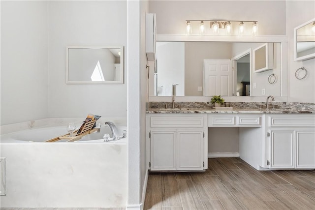 full bathroom featuring double vanity, a garden tub, and a sink