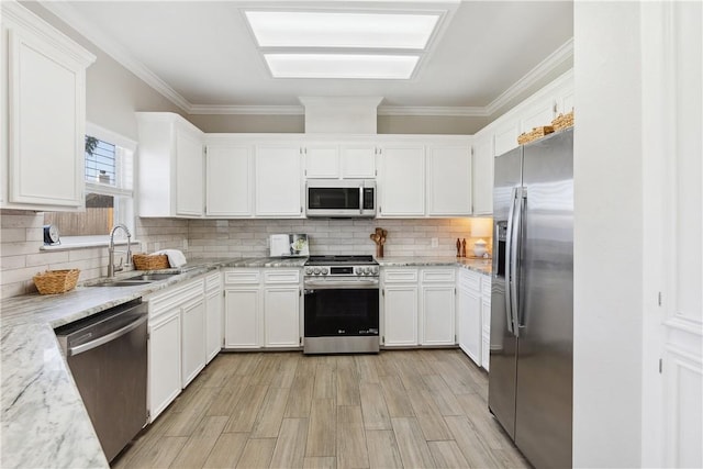 kitchen with a sink, decorative backsplash, white cabinets, appliances with stainless steel finishes, and crown molding