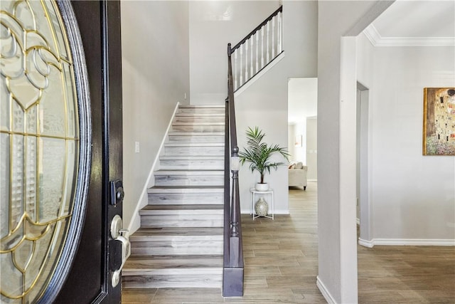 entryway featuring ornamental molding, stairs, baseboards, and wood finished floors