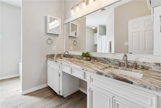 bathroom with visible vents, wood finished floors, baseboards, and a sink