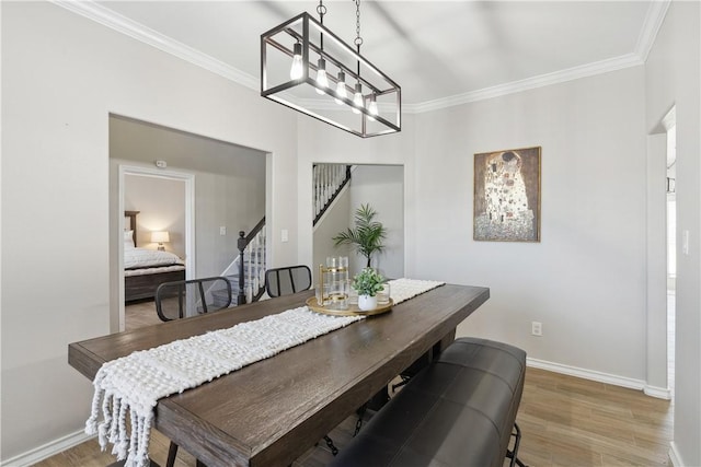 dining room with light wood-type flooring, baseboards, stairs, and crown molding