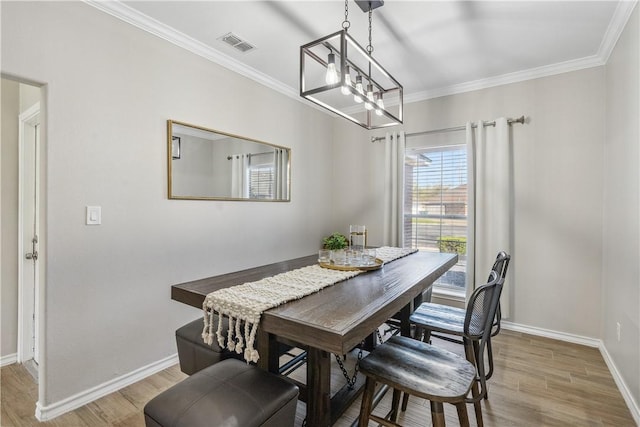 dining area with visible vents, baseboards, crown molding, and light wood-style floors