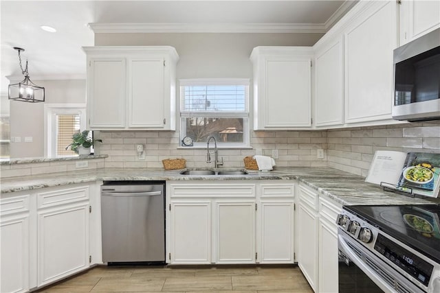 kitchen with a sink, tasteful backsplash, white cabinetry, appliances with stainless steel finishes, and crown molding