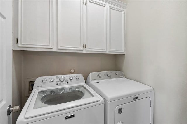 clothes washing area featuring cabinet space and washer and clothes dryer