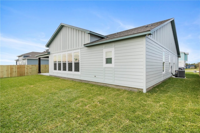 rear view of property featuring a lawn and central air condition unit