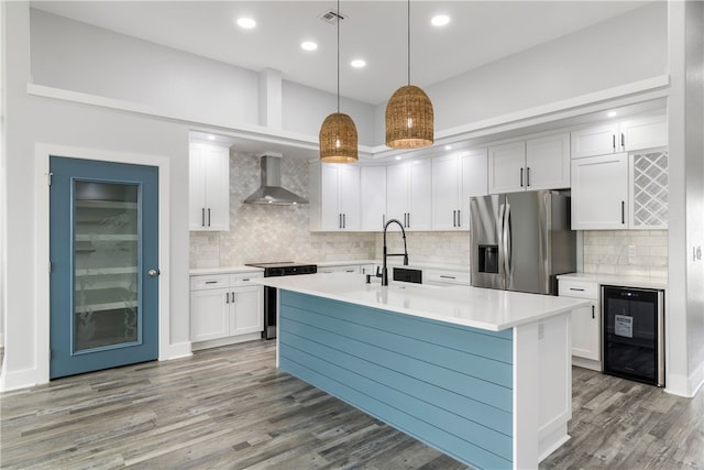 kitchen with stainless steel appliances, sink, wall chimney range hood, wine cooler, and hanging light fixtures