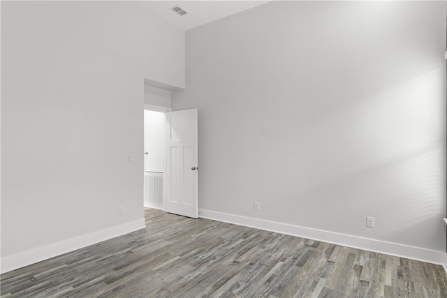 spare room with hardwood / wood-style floors and a high ceiling