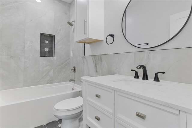 full bathroom with tiled shower / bath combo, toilet, tile walls, and vanity