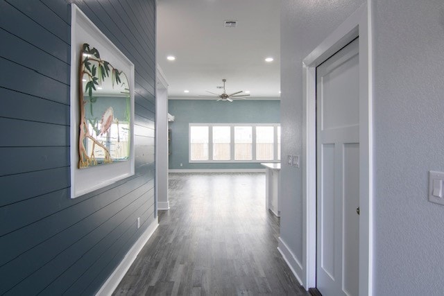 hallway with dark wood-type flooring and wood walls