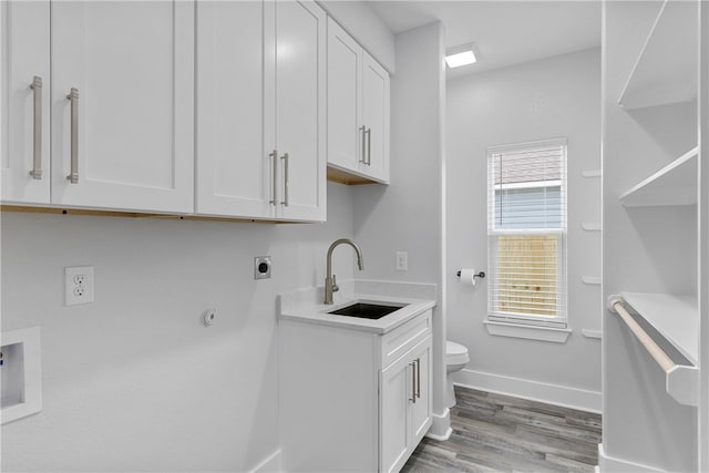 laundry room featuring electric dryer hookup, cabinets, gas dryer hookup, sink, and hardwood / wood-style flooring