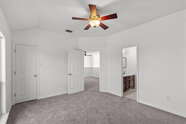 unfurnished bedroom with vaulted ceiling, light carpet, ceiling fan, and ensuite bath