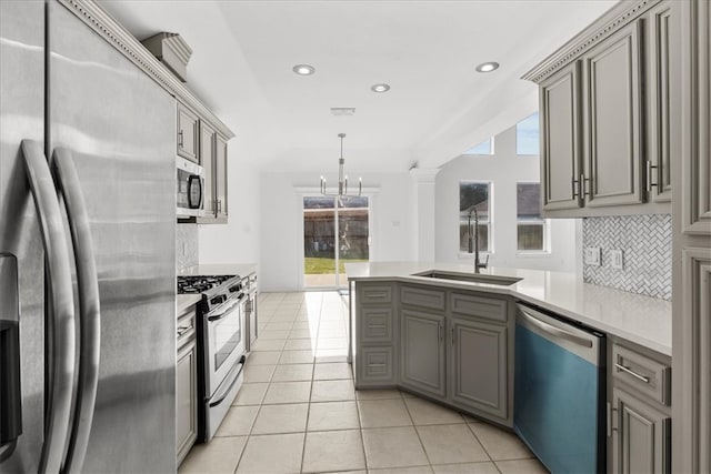 kitchen with stainless steel appliances, kitchen peninsula, hanging light fixtures, sink, and light tile patterned flooring