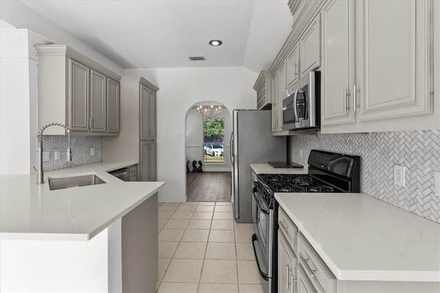 kitchen featuring light tile patterned flooring, sink, kitchen peninsula, appliances with stainless steel finishes, and decorative backsplash