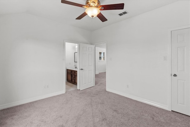 unfurnished bedroom with connected bathroom, vaulted ceiling, light colored carpet, and ceiling fan